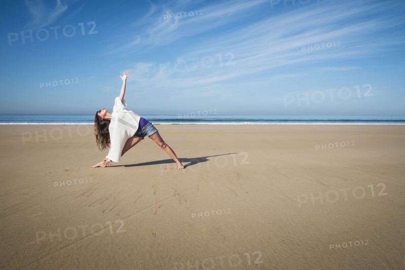 Caucasian woman practicing yoga on beach