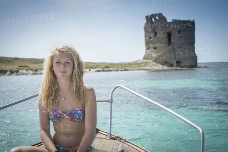 Smiling girl sunbathing on sailboat near ancient ruins