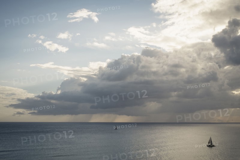 Sailboats under clouds on ocean