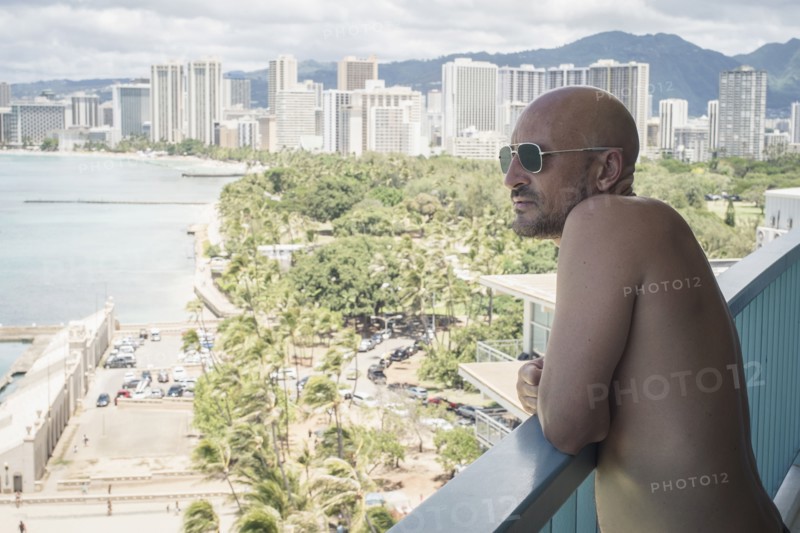 Caucasian man admiring urban ocean view from balcony