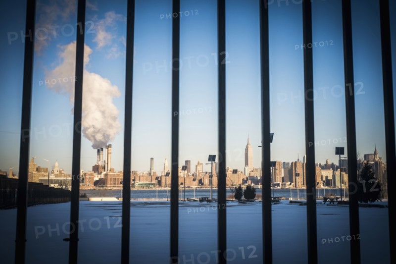 Bars in front of smokestack in city skyline