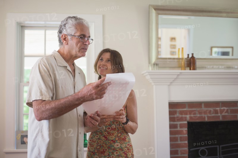Caucasian couple reading paper in living room