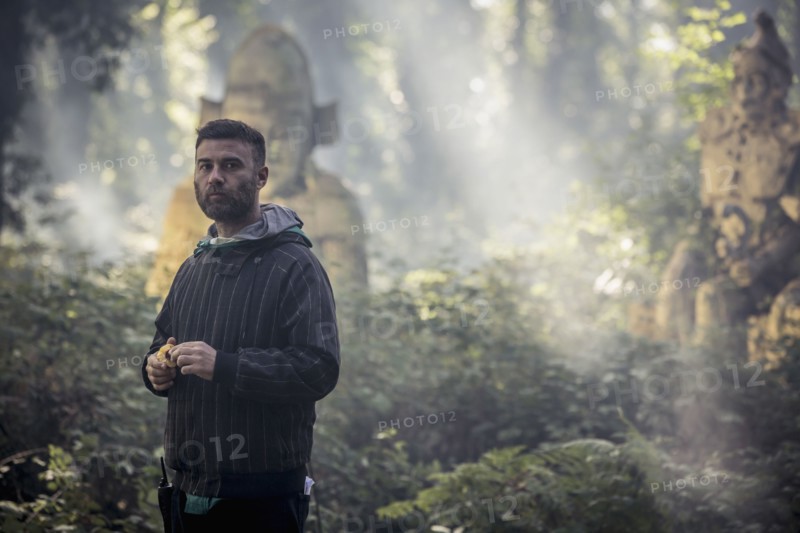 Caucasian man exploring ancient statues in forest