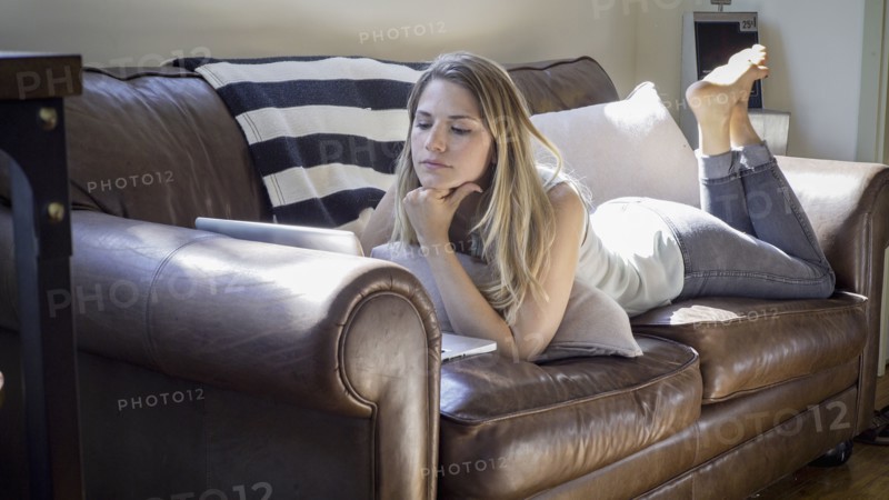 Caucasian woman using laptop on sofa