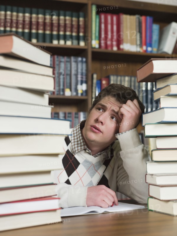 Student staring at stacks of books in library