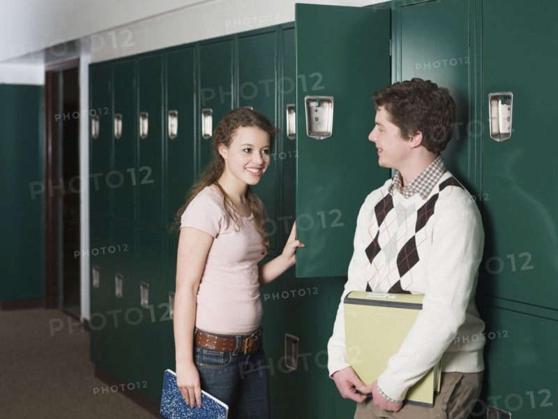 Students talking at locker in school hallway