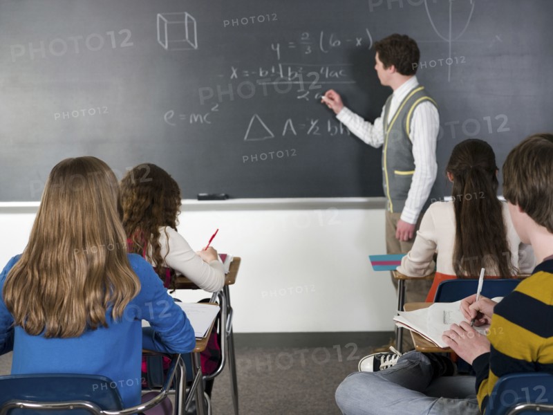 Teacher writing on chalkboard in classroom