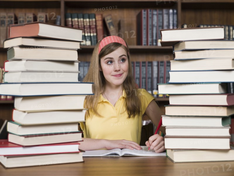 Student with stacks of books at desk in library