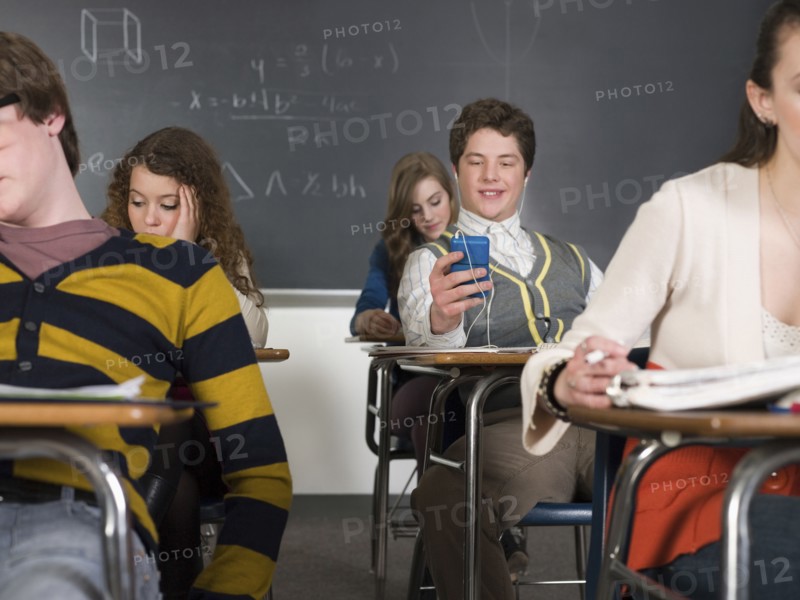 Student listening to earbuds at desk in classroom