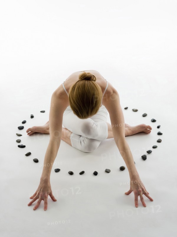 Caucasian woman practicing yoga in ring of stones