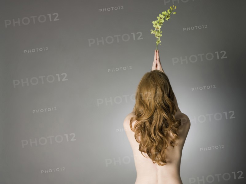 Rear view of nude Caucasian woman holding leaves