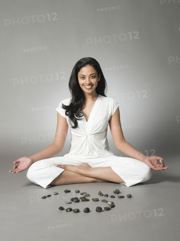 Smiling woman meditating by peace symbol in stones