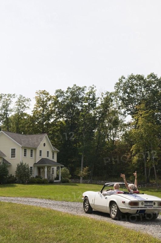 Rear view of older couple driving convertible