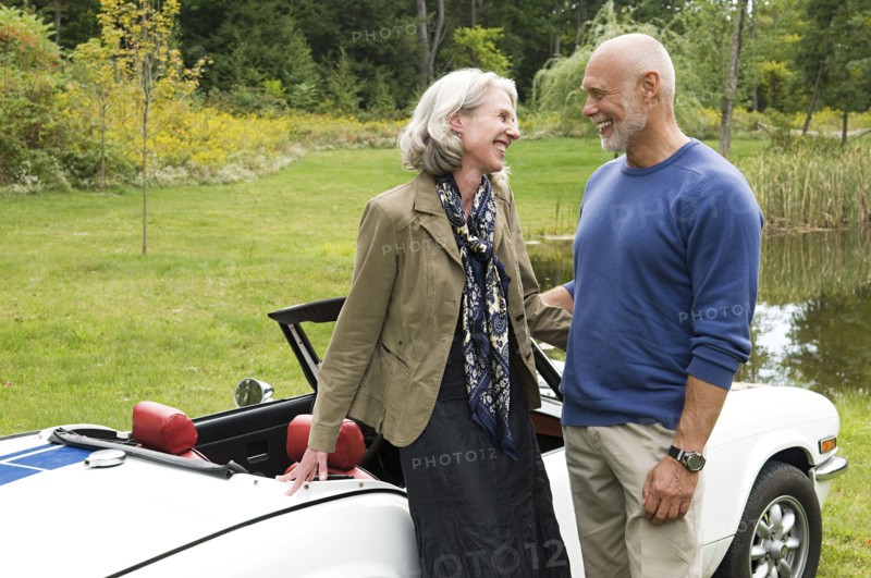 Older couple standing by convertible