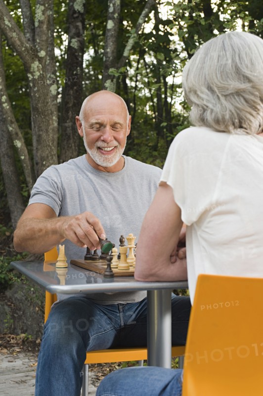 Older couple playing chess in backyard