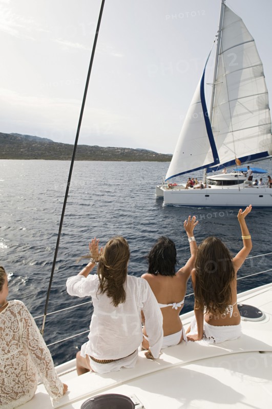 Women waving from sailboat on ocean