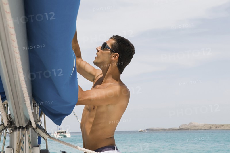 Man hoisting rigging on sailboat