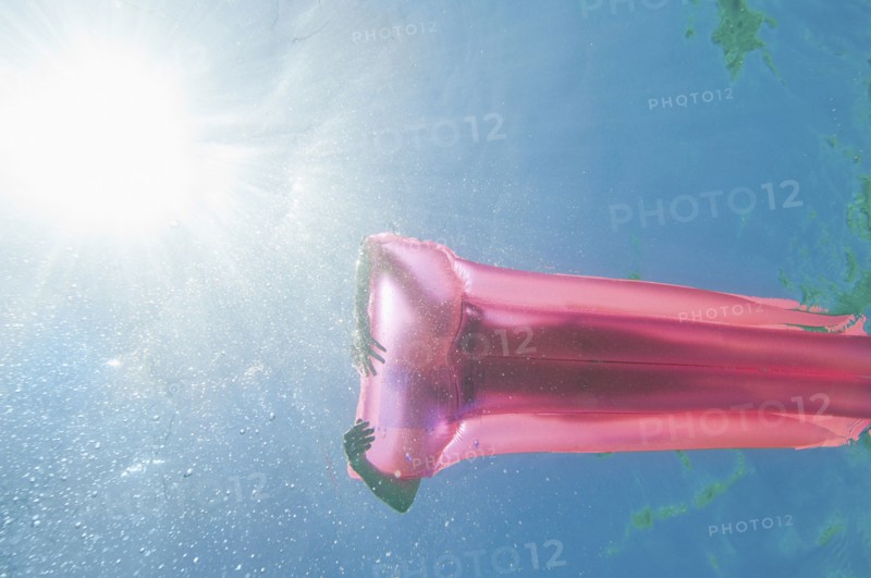 Underwater view of woman sunbathing on raft in ocean
