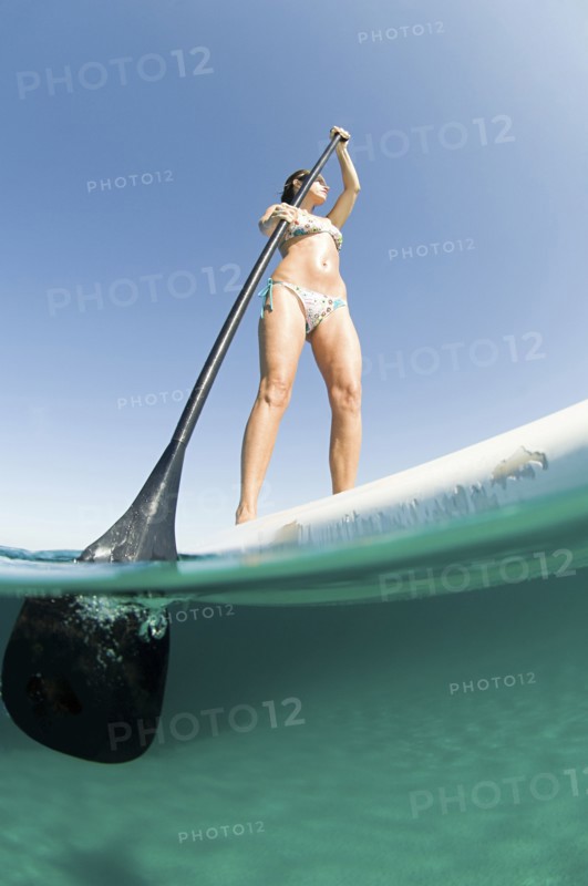 Low angle view of woman standing on paddle board