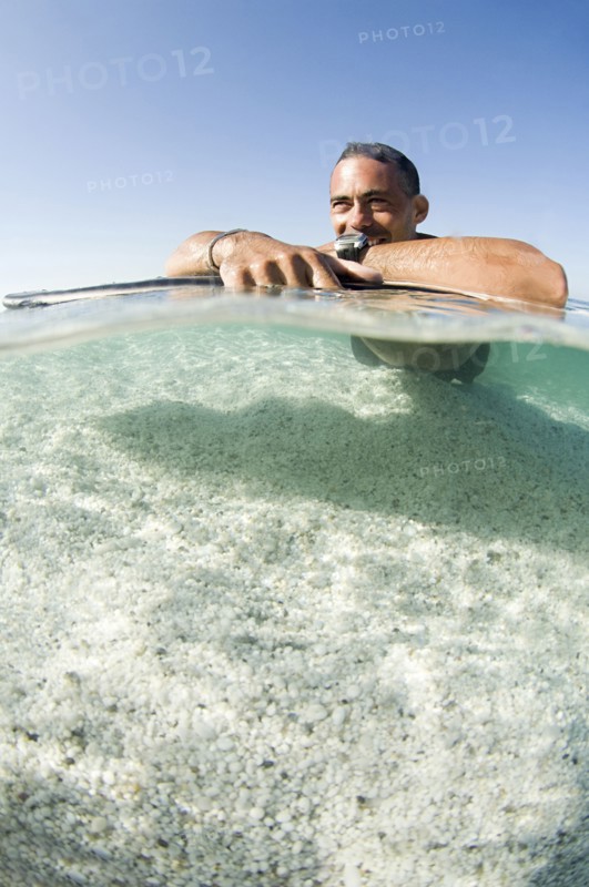 Close up of man laying on surfboard in ocean