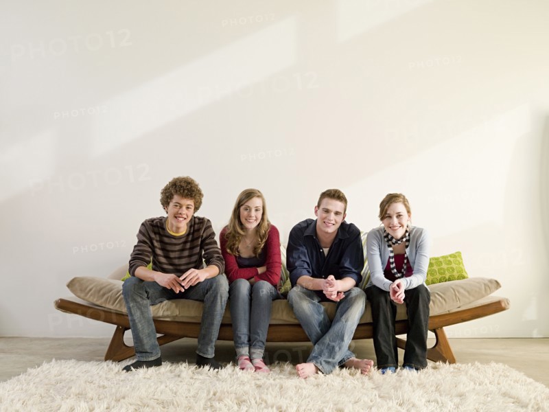 Friends sitting on modern sofa in living room