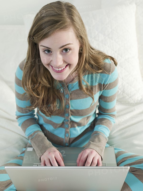 Caucasian woman using laptop on bed