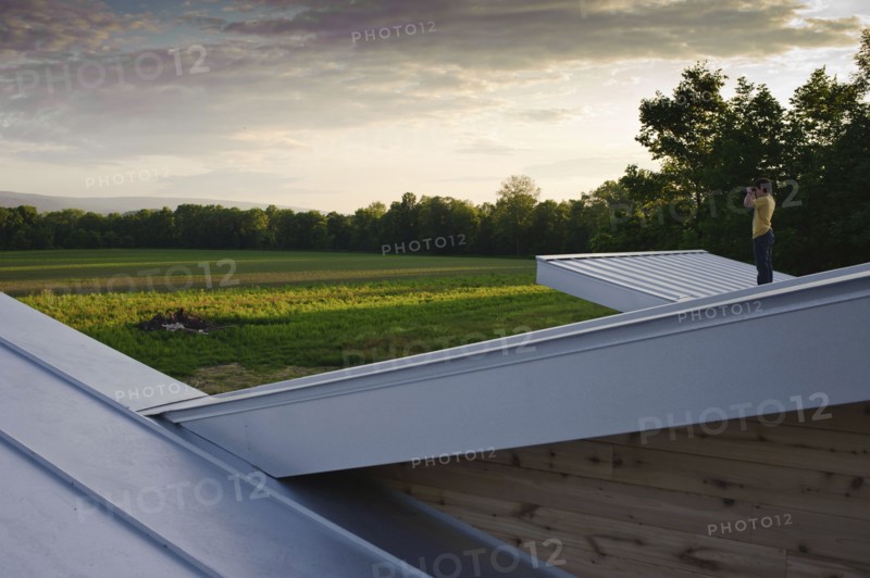 Man on roof admiring view of rural field