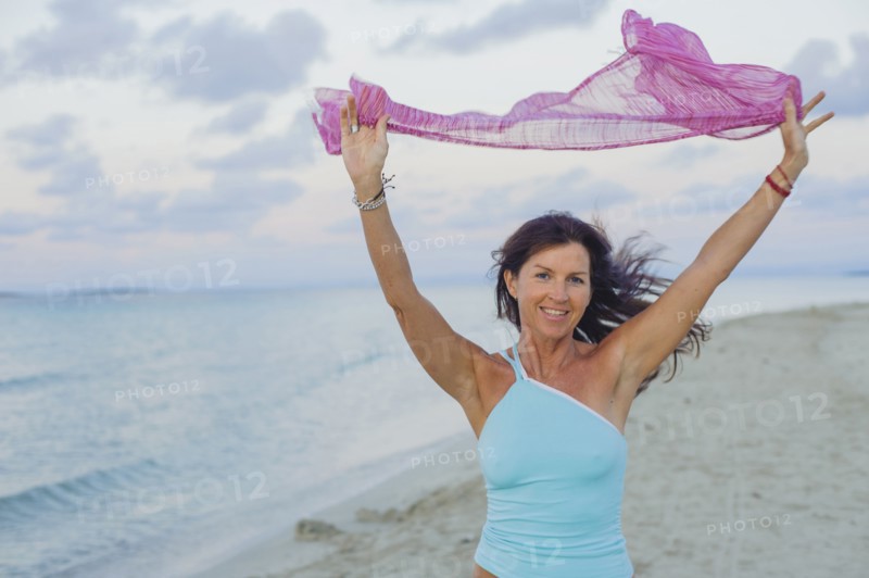 Caucasian woman playing with scarf on beach