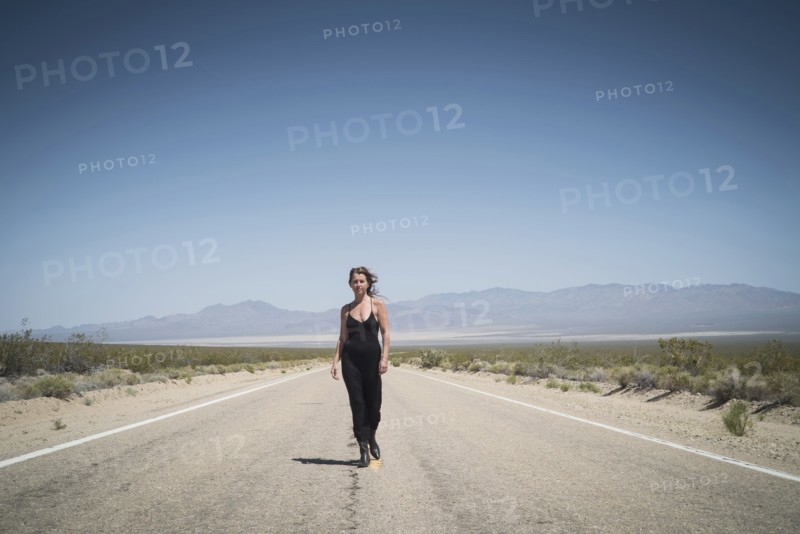 Caucasian woman walking on remote desert road