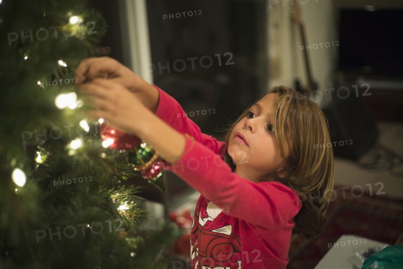 Caucasian boy hanging ornament on Christmas tree