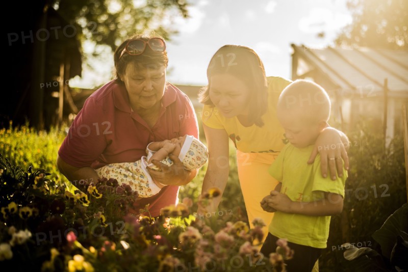 Caucasian family examining flowers in garden
