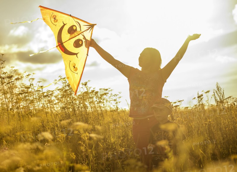 Caucasian mother and son flying kite in rural field