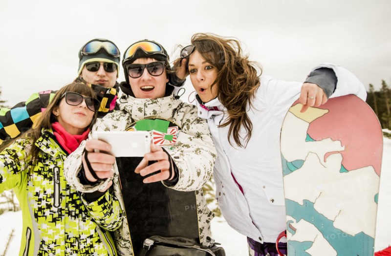 Caucasian friends with snowboard taking selfie