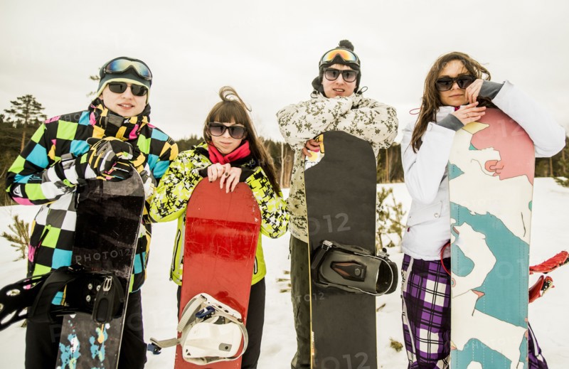 Caucasian couples holding snowboards in snow