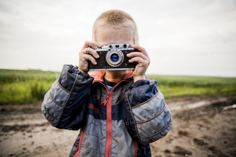 Caucasian boy taking photograph in rural field