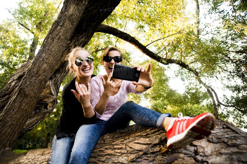 Caucasian women taking cell phone selfie in tree