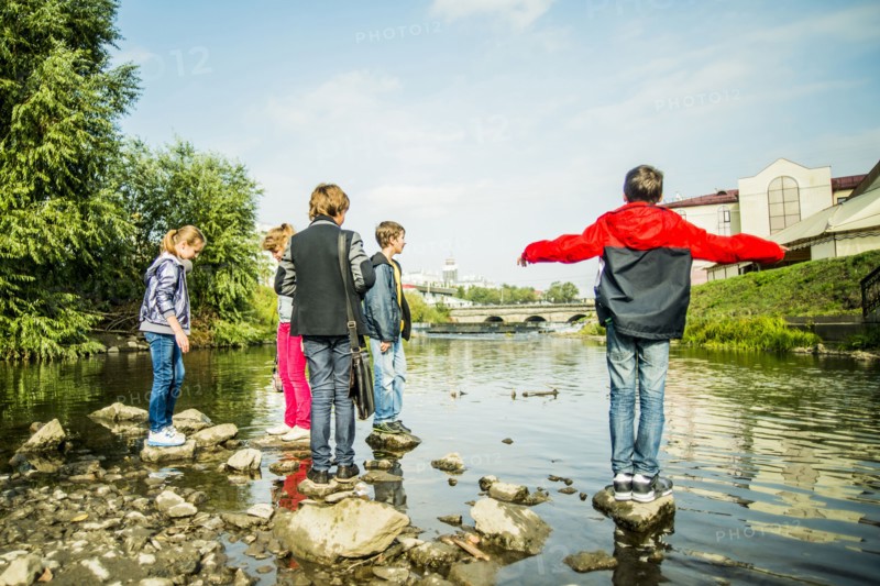 Caucasian children playing on rocks in river
