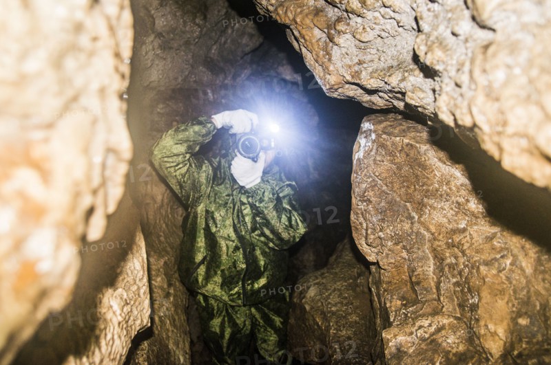 Caucasian man taking photograph in rock formation cave