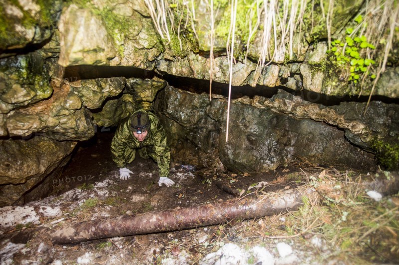 Caucasian man climbing out of rock formation cave