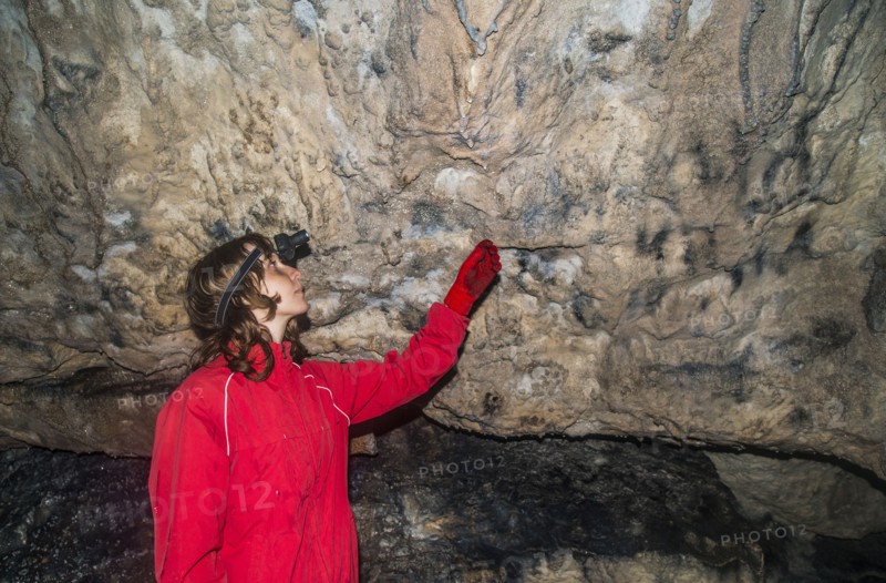 Caucasian woman admiring rock formations in cave