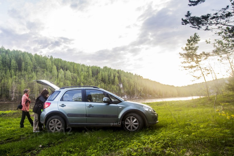 Caucasian tourists unloading car in remote landscape