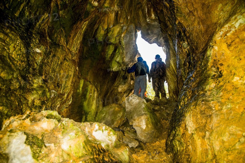 Caucasian men exploring rock formation cave