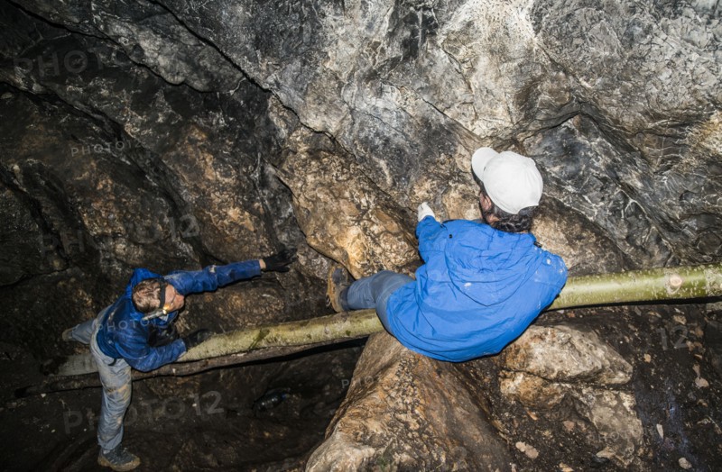 Caucasian climbers exploring rock formation cave