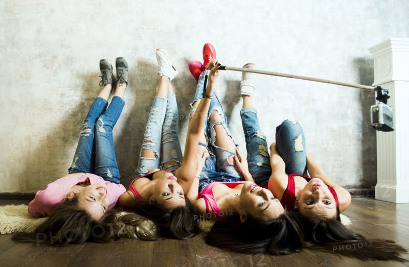 Caucasian women taking cell phone selfie on floor