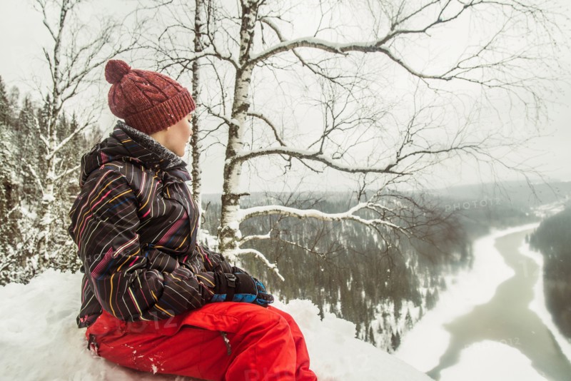 Caucasian hiker sitting on snowy hilltop