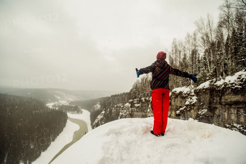 Caucasian hiker standing with arms outstretched on snowy hilltop