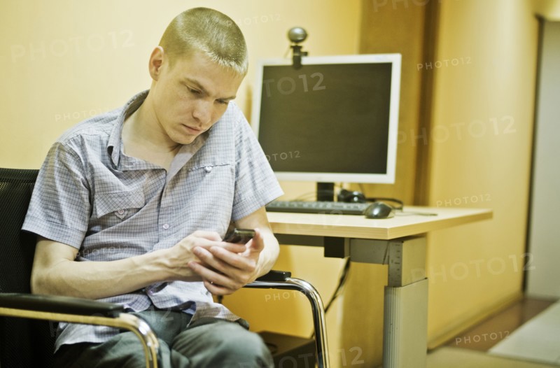 Caucasian man using cell phone at computer desk