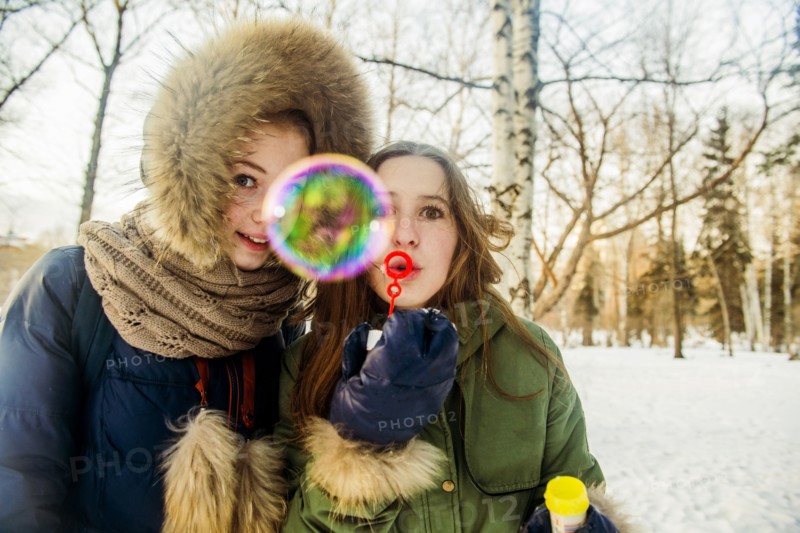Caucasian women blowing bubbles in snowy field