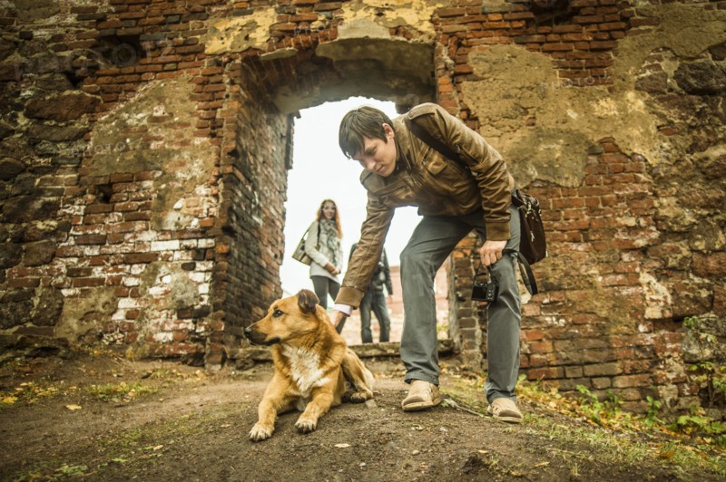 Caucasian man petting dog near ruins