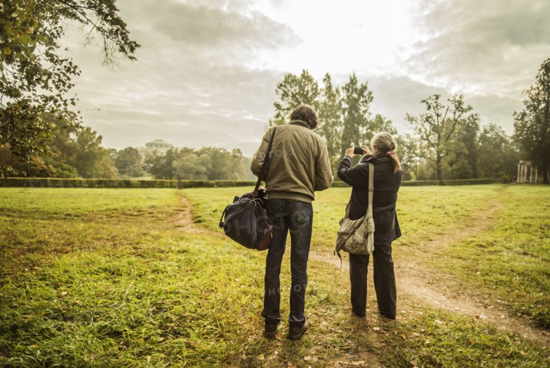 Caucasian couple standing on trail in park with camera